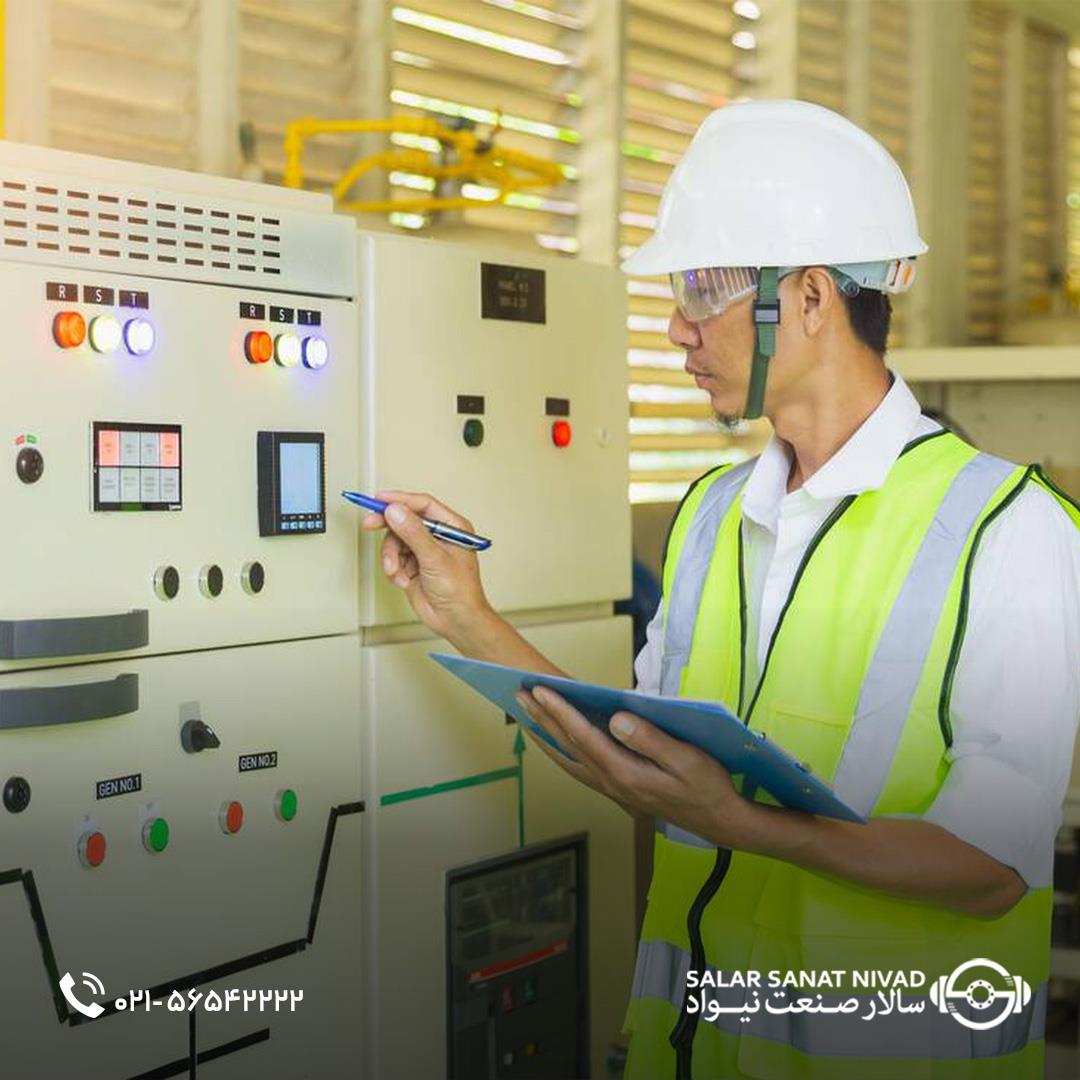 مهندس برق با کلاه ایمنی و جلیقه شبرنگ در حال بررسی تابلو برق صنعتی و یادداشت اطلاعات